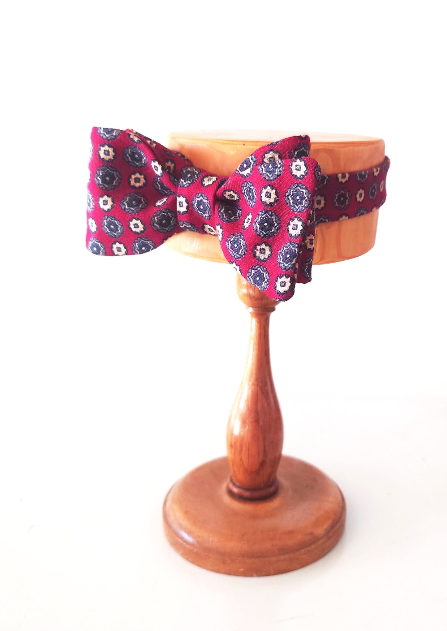 Floral-patterned bow tie on a wooden stand against a white background by lewesbowties.co.uk