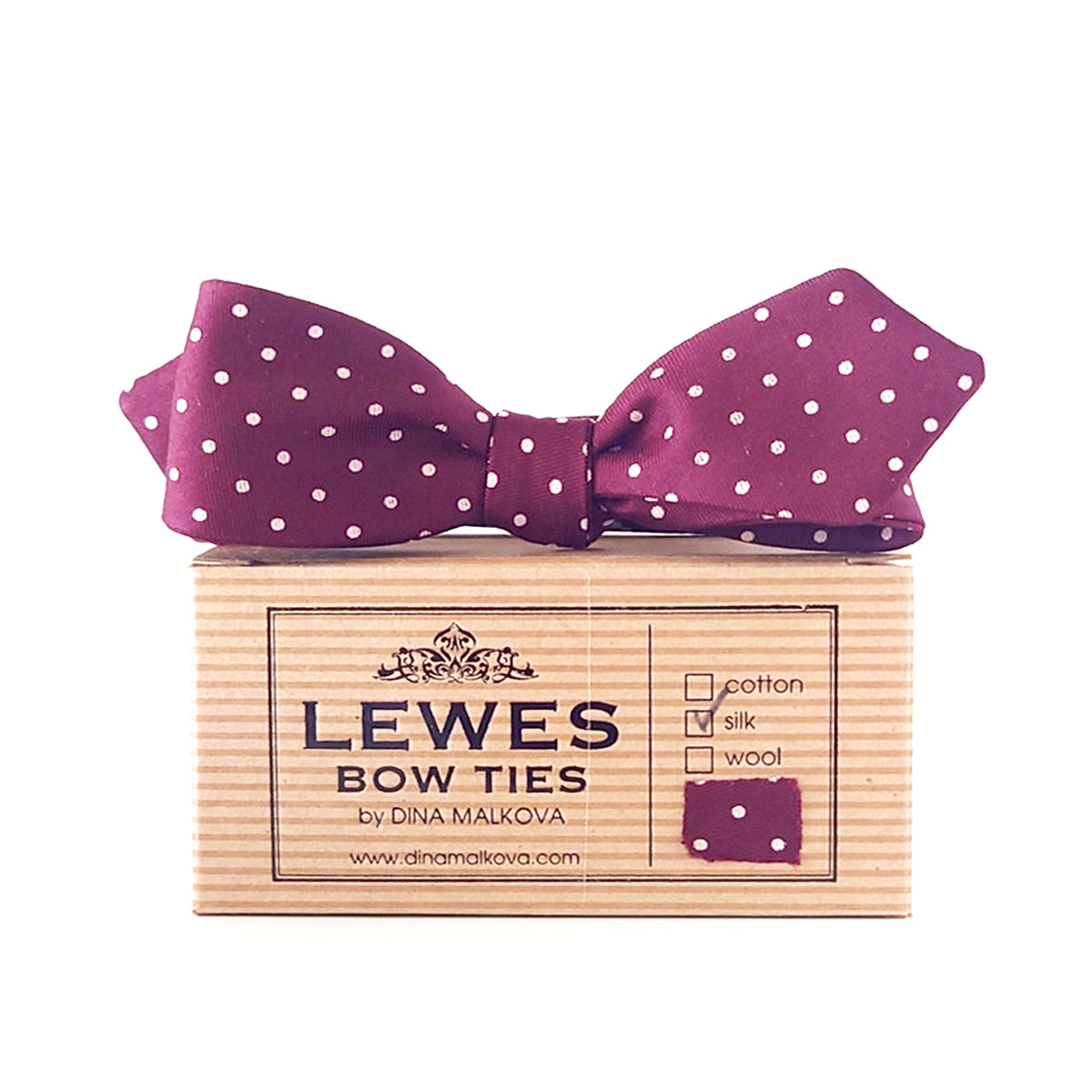 A burgundy silk bow tie with white polka dots, presented on top  'LEWES BOW TIES box