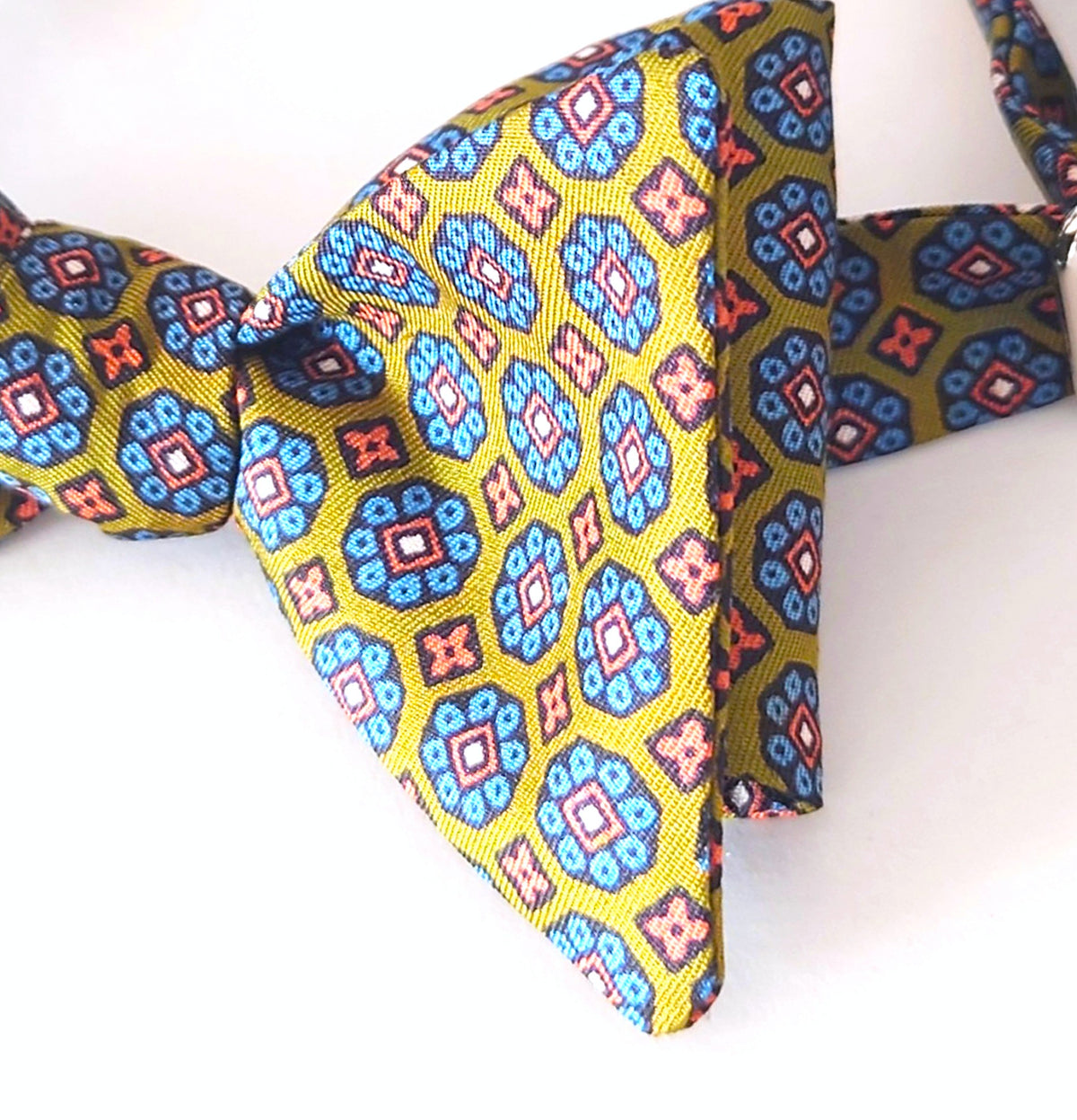 Olive green silk bow tie with repetitive pattern in blue and orange.