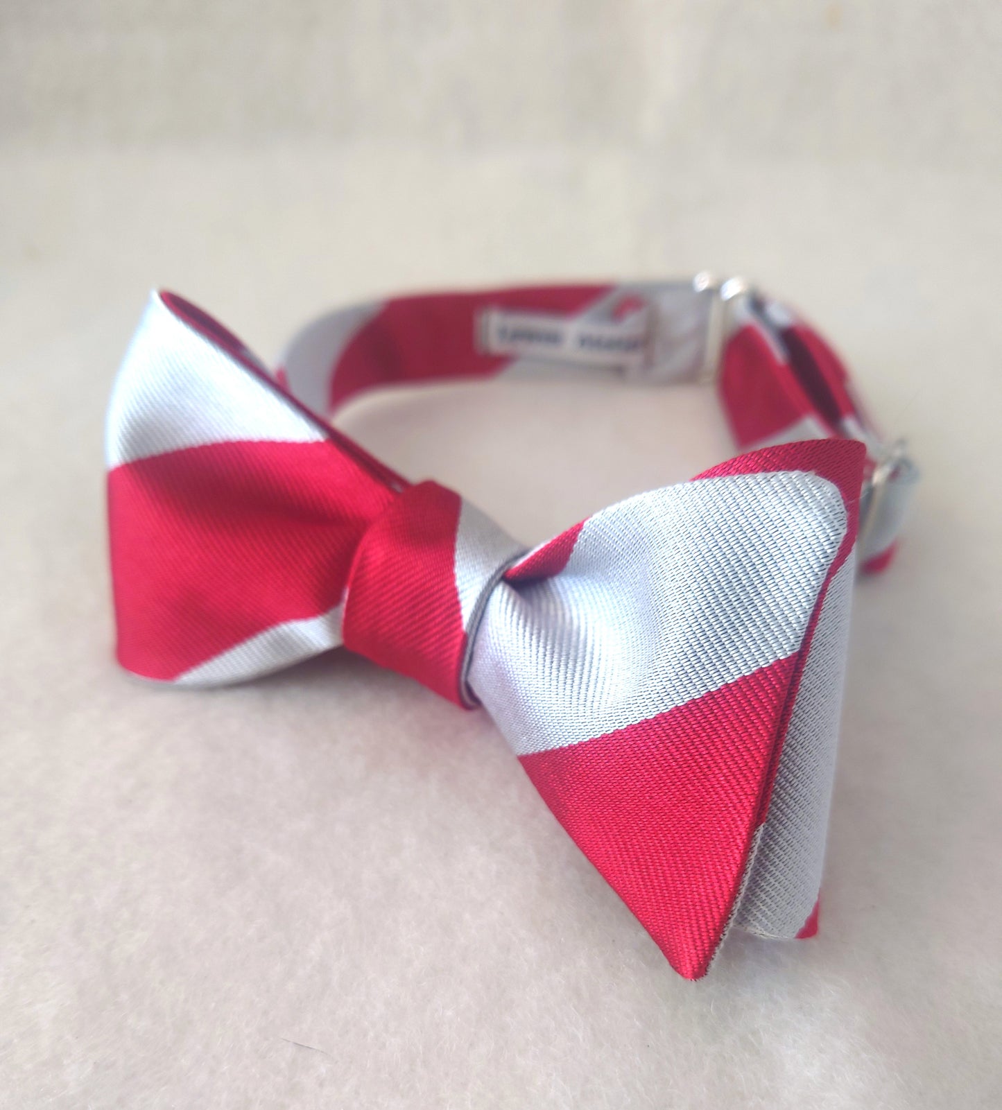 Red and white striped silk bow tie on a light background, a perfect Christmas bow tie