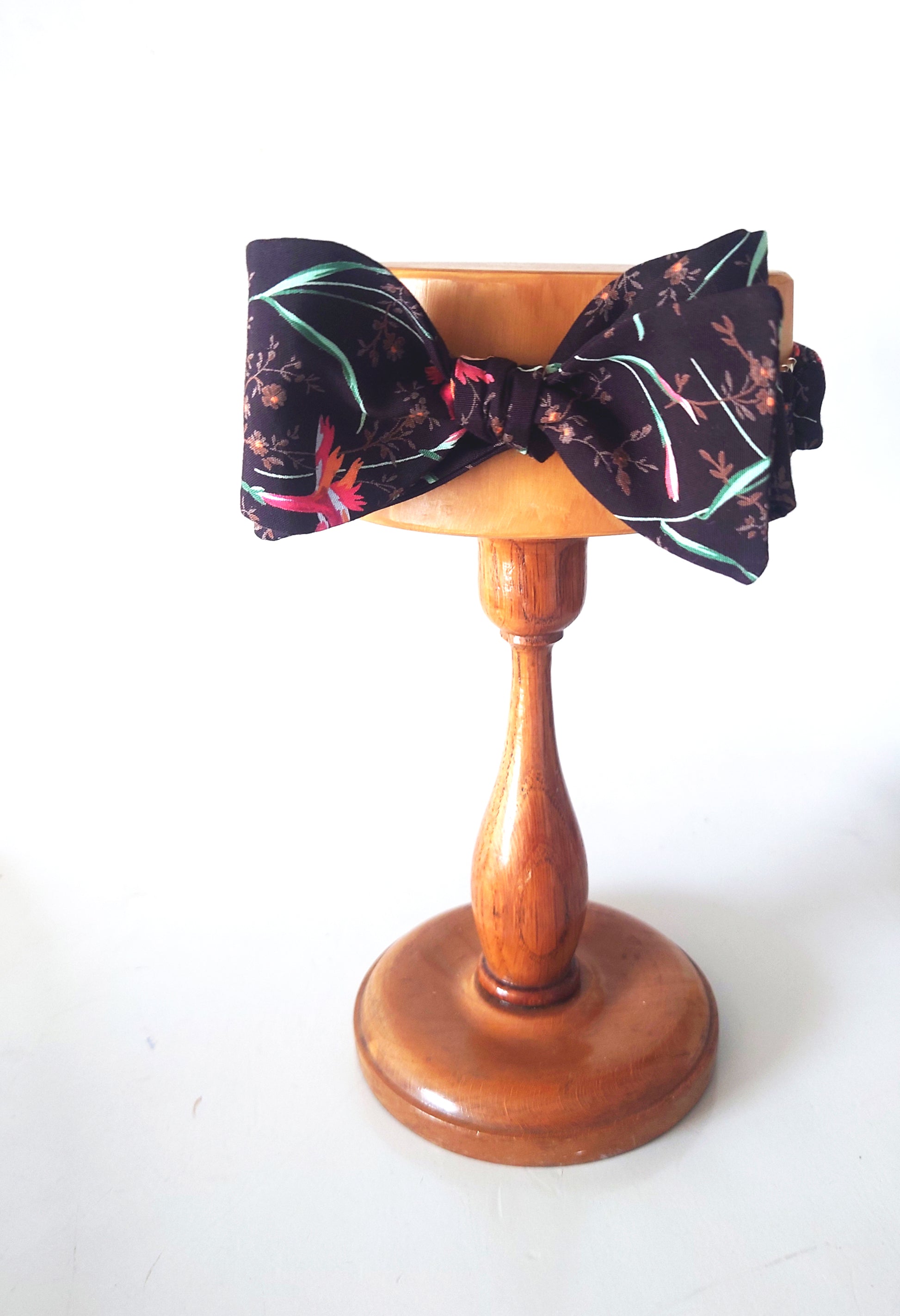 Pink carnations on brown cotton bow tie on stand