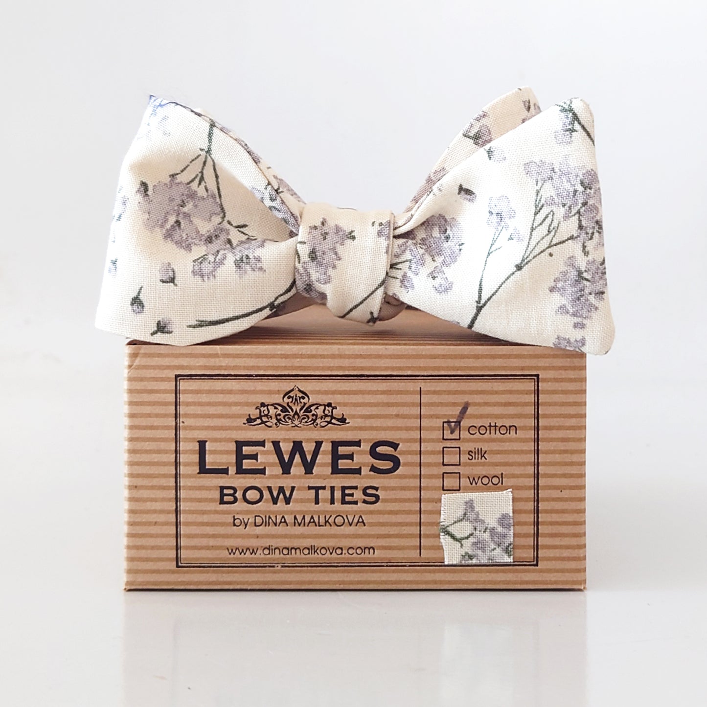 Floral bow tie on a box with 'Lewes Bow Ties' branding.